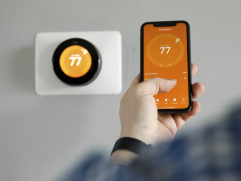 A man using his phone to adjust the thermostat